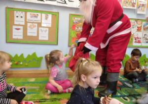 Mikołaj częstuje dziewczynkę cukierkami